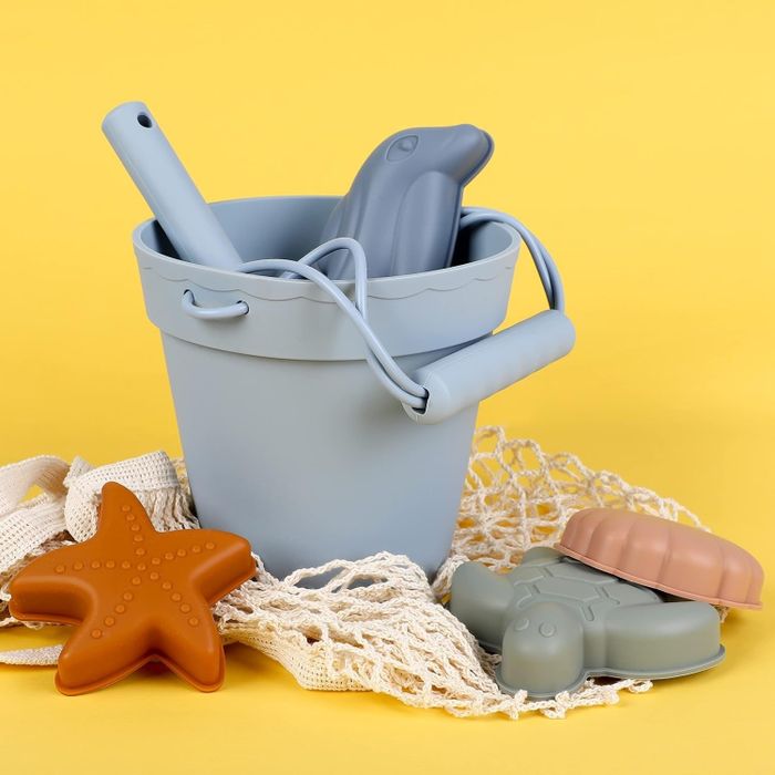A beach bucket toy set featuring a blue bucket, toy shovel, starfish, turtle, and more.