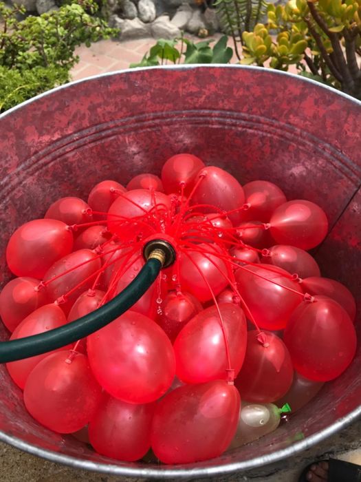 Reviewer image of a hose filling up a bunch of red self-sealing water balloons