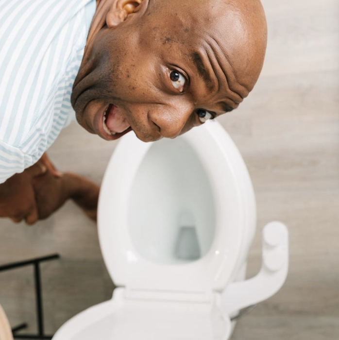 A model pulling a silly face while leaning over the toilet seat.