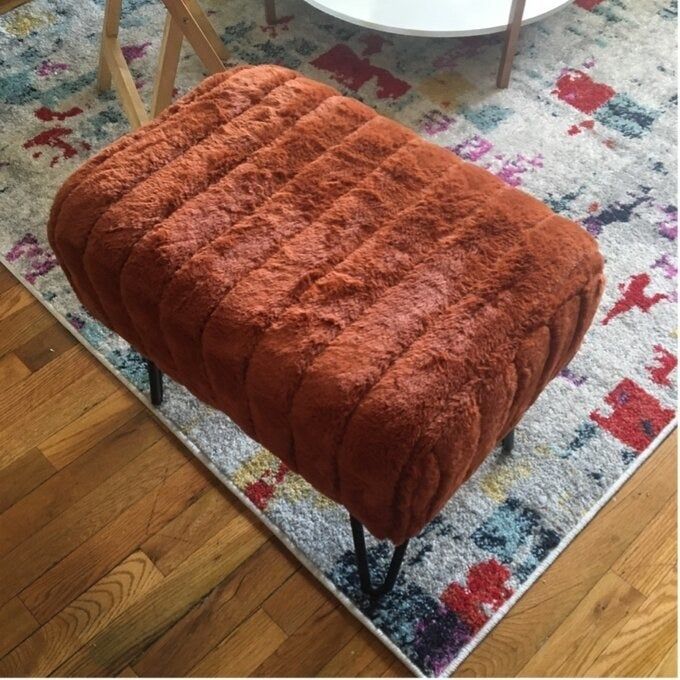 The plush ottoman in a warm, rusty orange hue.