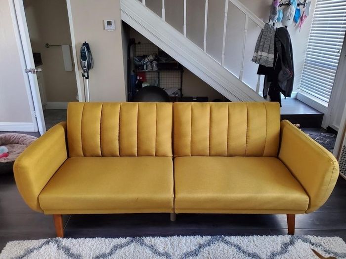 The Novogratz futon shown in a smooth, creamy mustard color
