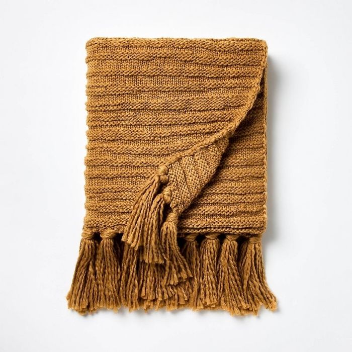 A dark tan throw blanket with tassels.