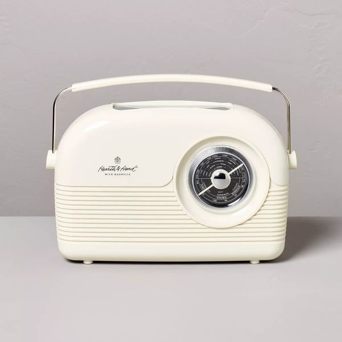 A white vintage-style tabletop radio from Hearth & Hand with Magnolia, featuring a round dial, displayed on a grey surface.