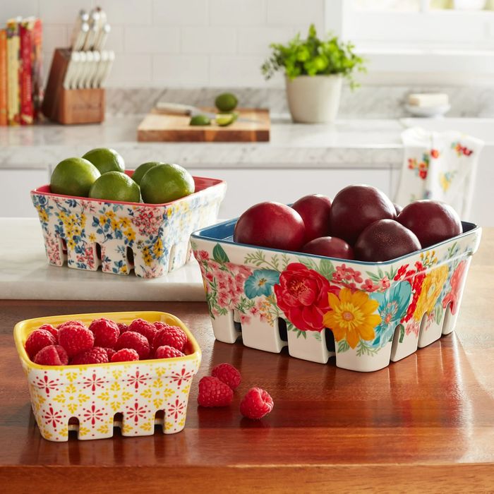 Three ceramic baskets holding limes, plums, and raspberries, displayed on a kitchen counter — perfect for decorative storage or serving purposes