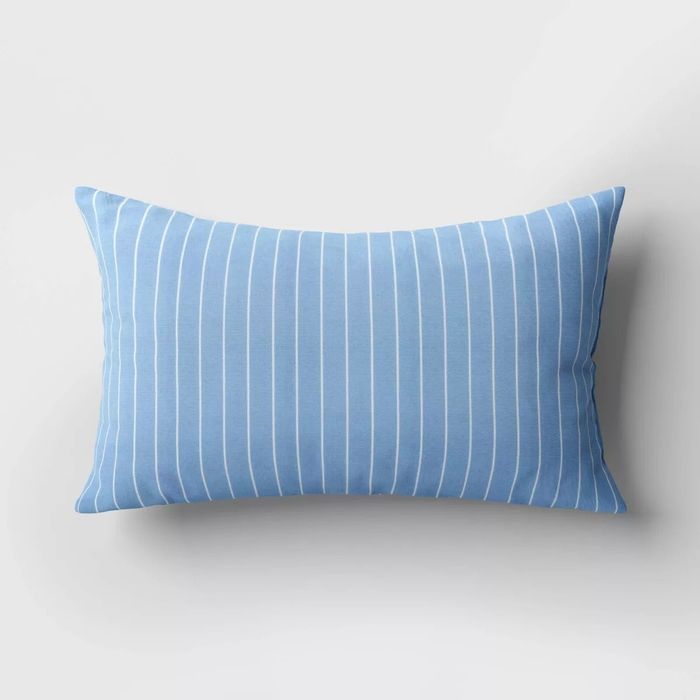 A rectangular pillow featuring vertical white stripes on a soft, light backdrop, making it an excellent addition to home decor.