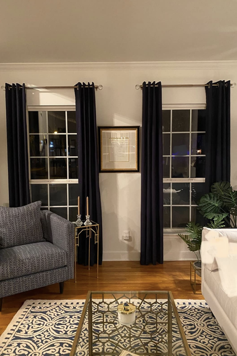 The reviewer's curtain rods are used to drape two windows in a living room