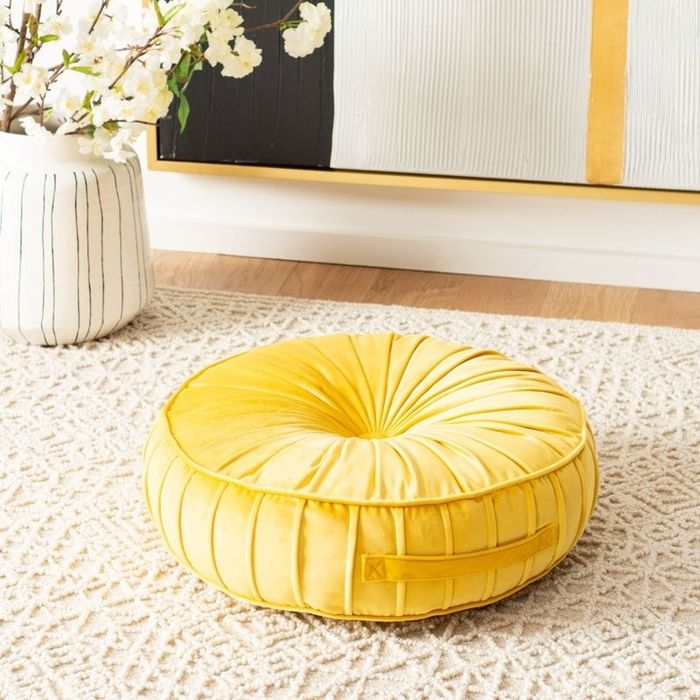 A cheerful yellow pillow resting on the floor.