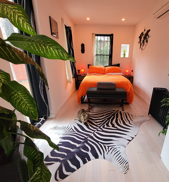A zebra-patterned rug positioned at an angle on the floor of the reviewer's compact bedroom.
