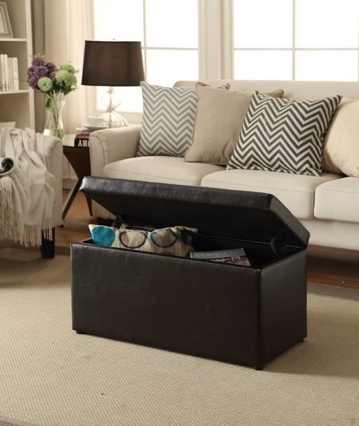 The brown ottoman, filled with pillows and magazines tucked neatly inside.
