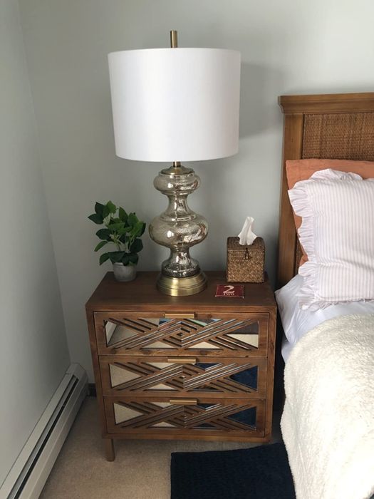 The wooden three-drawer table featuring mirrored drawers with geometric accents