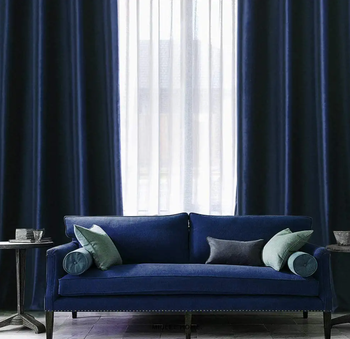 Two navy blue velvet curtains draped behind a couch