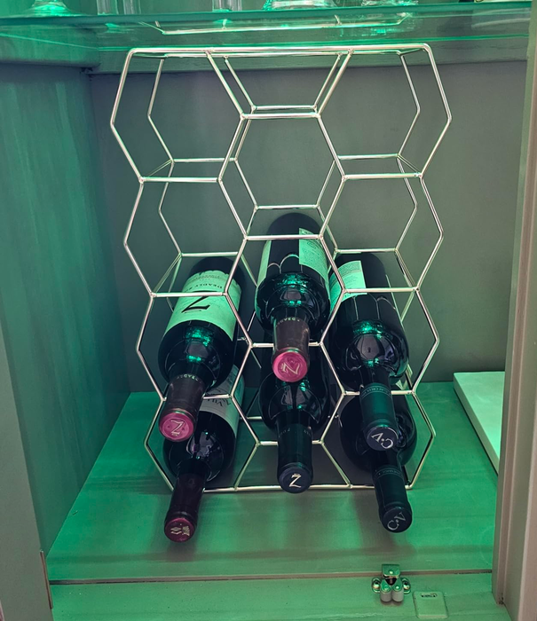 A reviewer’s gold hexagonal wine rack holding several bottles, showcased inside an illuminated cabinet as part of their home decor