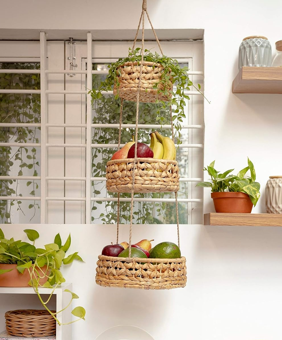 Three-tiered hanging wicker baskets filled with fresh fruit, suspended above a kitchen countertop