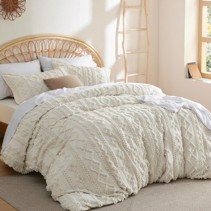 An elegant, textured comforter set with decorative pillows on a bed, perfect for upgrading your cozy bedroom