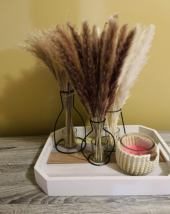 Three vases filled with long-stemmed feathers, creating an elegant display.