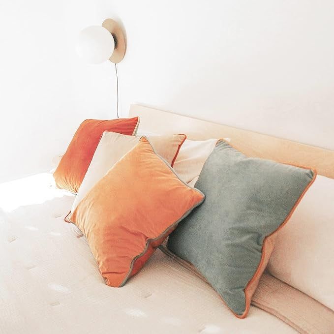 Velvet color block pillow covers placed on four throw pillows atop a bed
