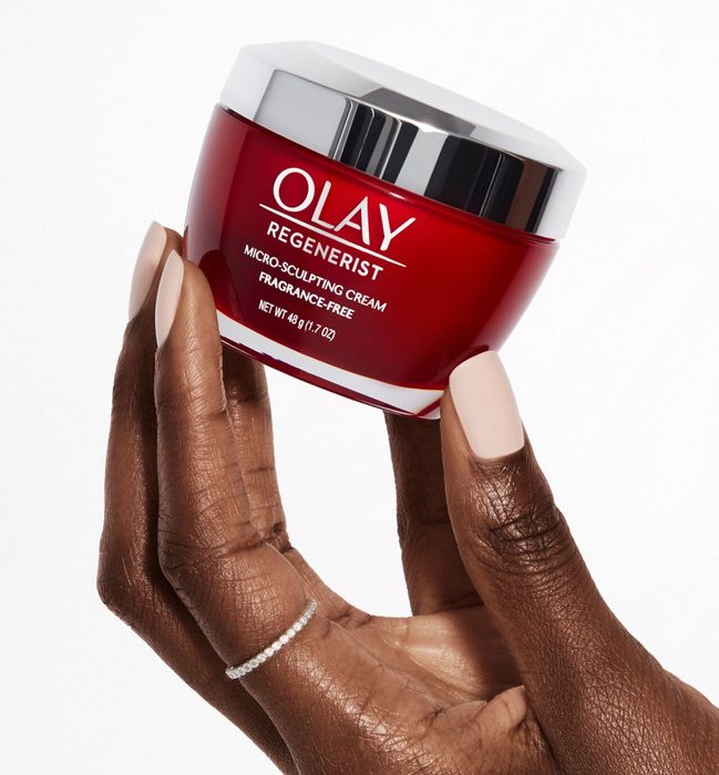 hand holding the red jar of moisturizer