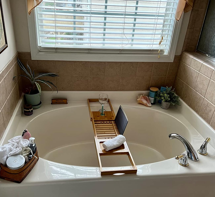 Another reviewer's bathtub with a wooden caddy tray over it, holding a glass of wine, a towel, and a book