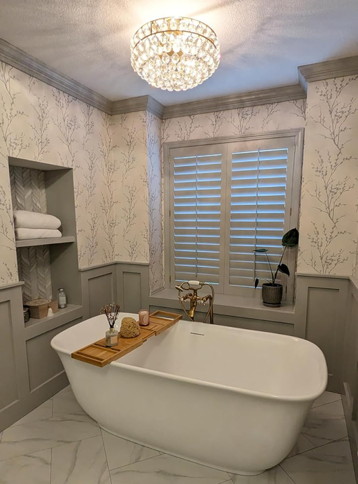 Reviewer's chic bathroom featuring a freestanding tub and a wooden tray placed across it