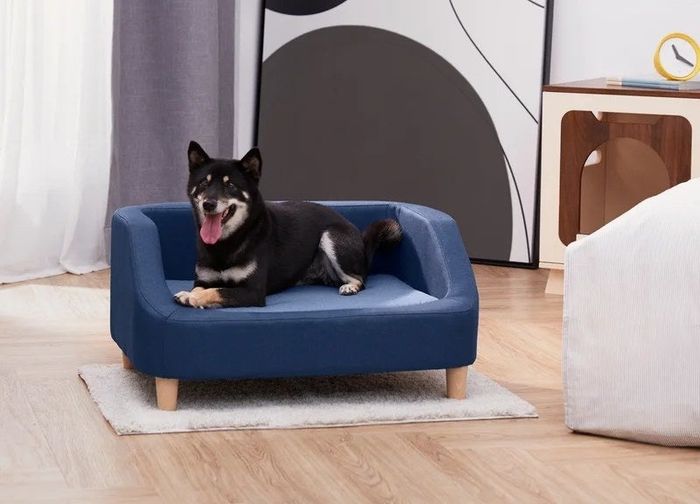 A dog comfortably lounging on a navy dog bed in a home, enjoying its stylish design and comfort.