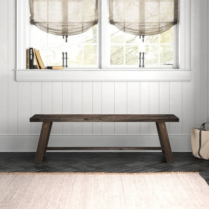 A medium brown bench positioned under a window, offering both functionality and style.