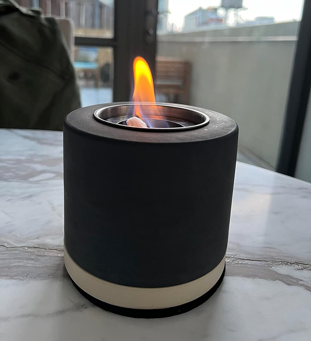 A small black tabletop fireplace with a flickering flame at its center, as shown by the reviewer