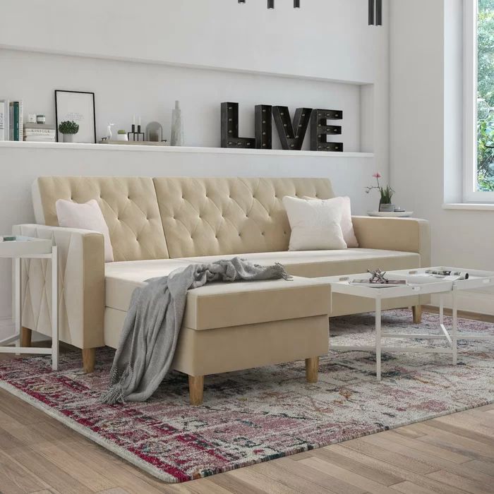 A cozy living room setup featuring an ivory sofa with a chaise lounge, accented with stylish throw pillows, a minimalist white side table, and a plush rug.
