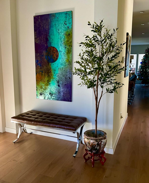 The reviewer’s faux olive tree is placed next to a bench, accompanied by a lovely art piece.