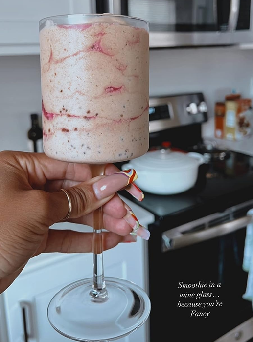 The reviewer holding up a glass filled with a pink smoothie
