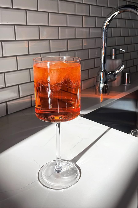 A glass filled with a vibrant orange drink, placed on a counter with sunlight streaming across it