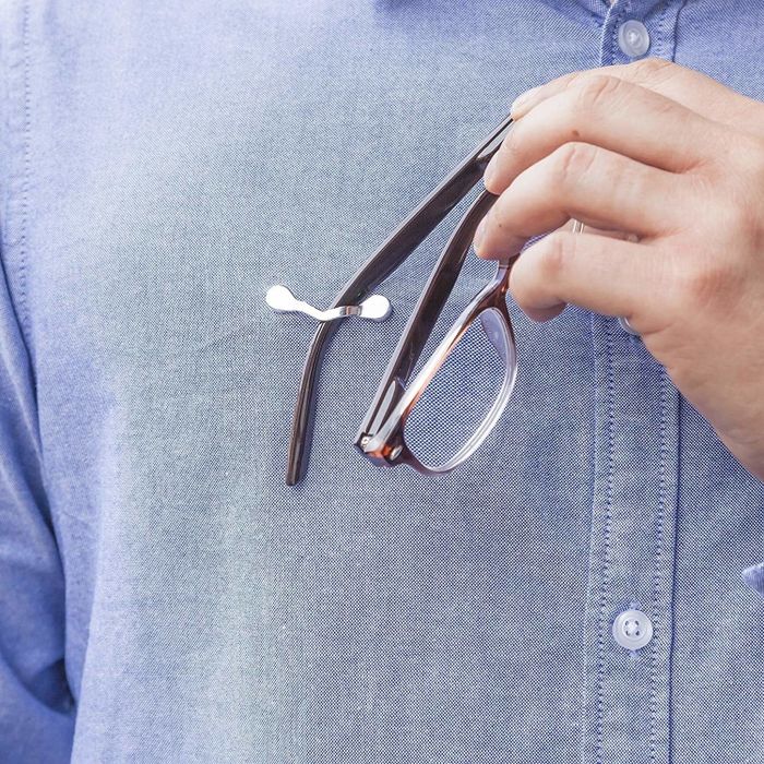 A person places their glasses onto a metal bar attached to a shirt's collar