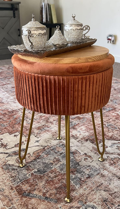 A reviewer's vibrant orange velvet ottoman topped with a vintage-style tea set