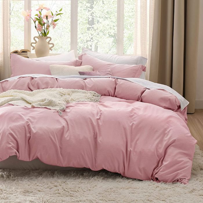 A soft pink duvet set laid out on a bed.