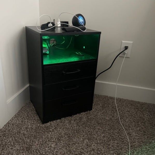 A black cabinet with LED lighting, perfect for storing tech equipment, positioned near a power outlet.