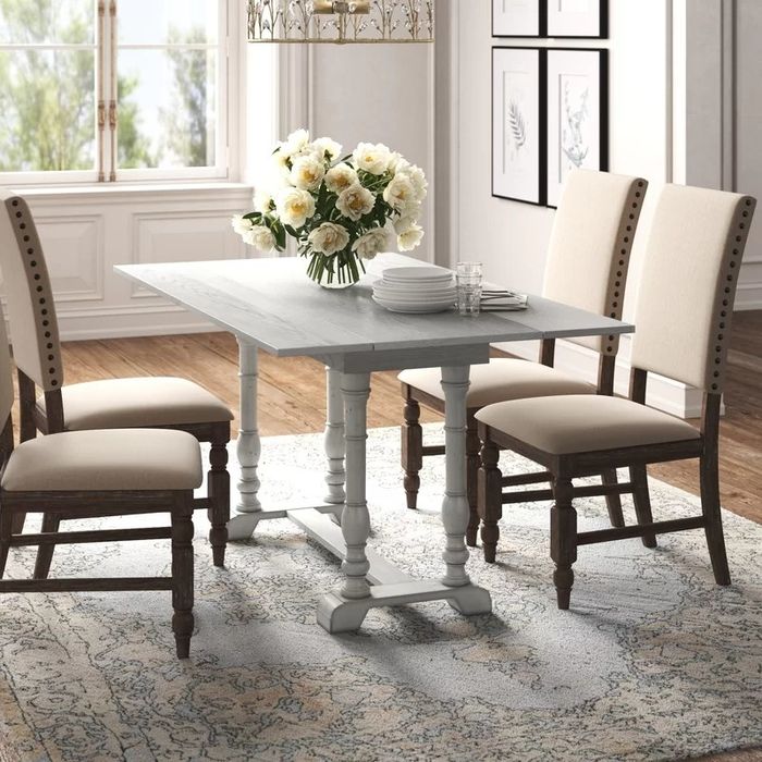 A white dining table with both leaves extended, surrounded by chairs, creating an inviting and spacious dining area.