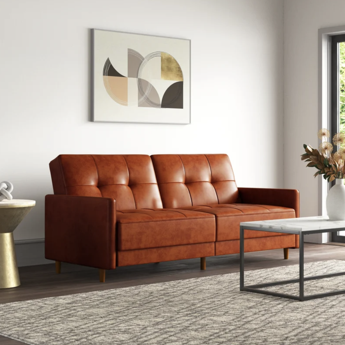 A stylish modern living room with a brown leather sofa, a geometric art piece adorning the wall, a marble coffee table, and a chic side table