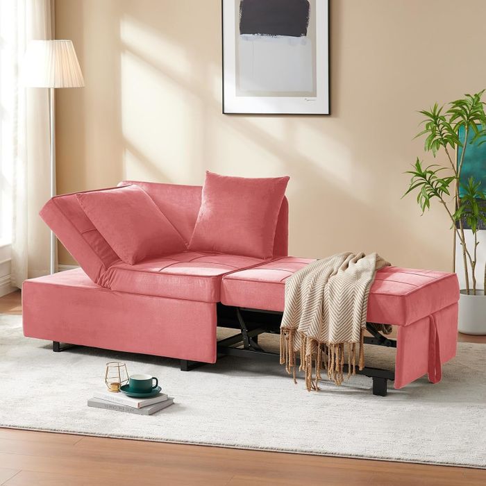 A modern pink sectional sofa with an adjustable backrest, complemented by a fringed throw. In the background, a potted plant and framed art add to the ambiance.