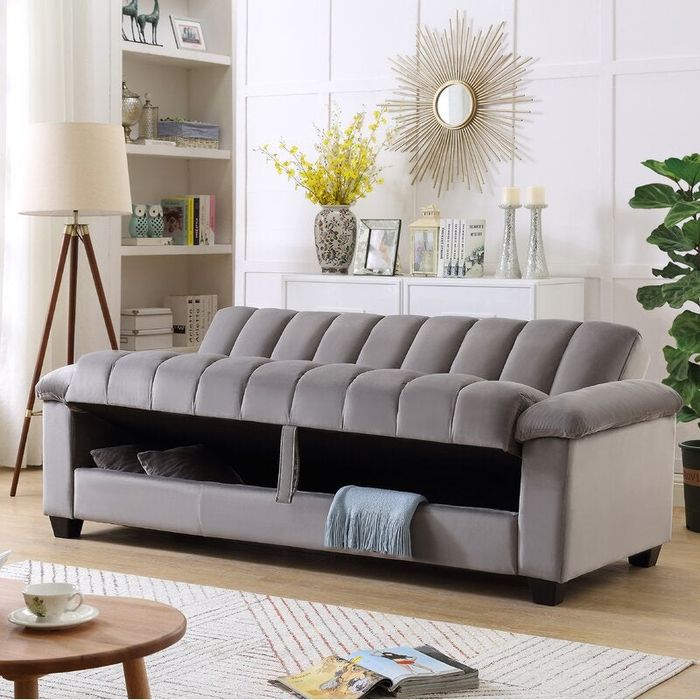 lifestyle shot of the couch in gray, highlighting the hidden storage space underneath