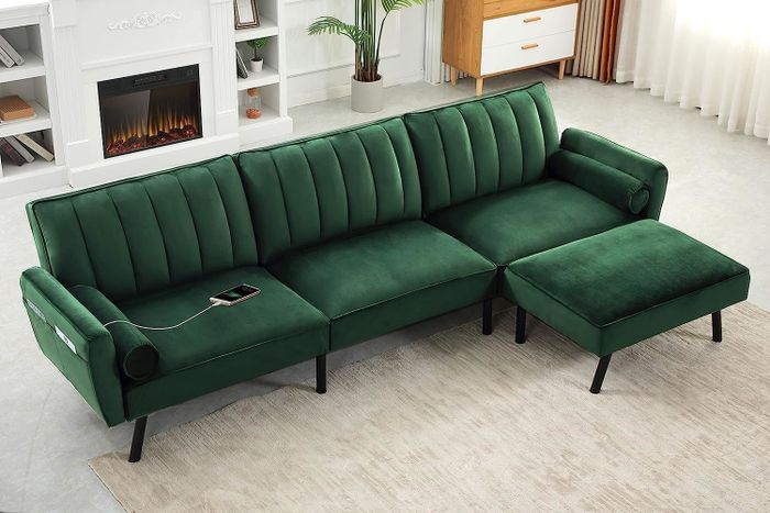 An elegant, modern velvet sofa paired with a matching ottoman, set in a stylish living room with a fireplace and minimalist decor.