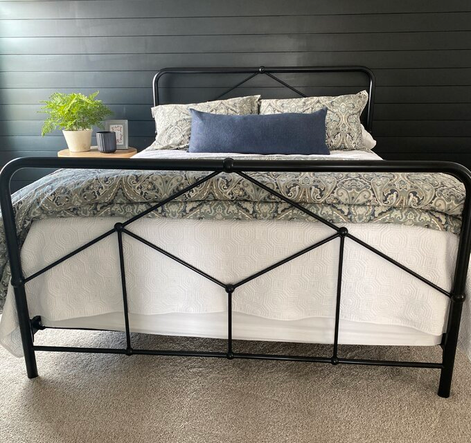 A reviewer's photo of a sleek black farmhouse bed frame in a cozy bedroom.