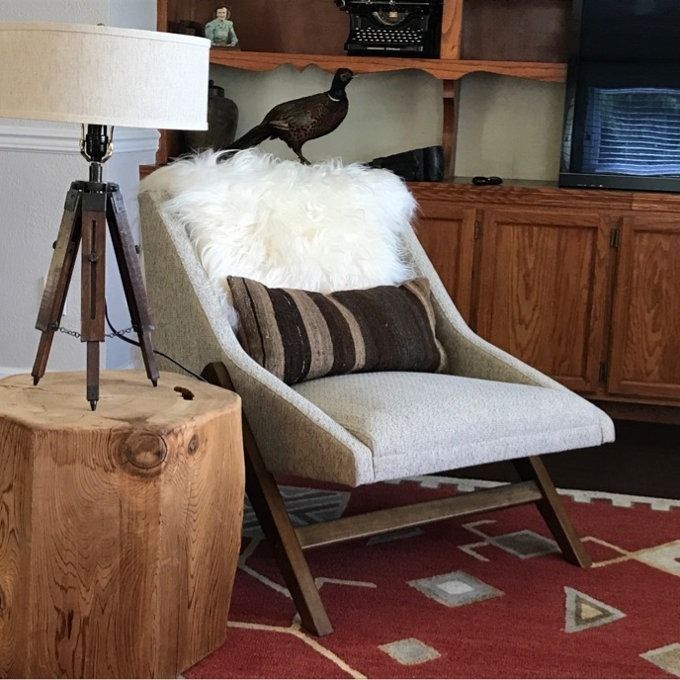 A cozy living room arrangement featuring a plush chair, a striped cushion, a soft fur throw, a wooden side table, and a lamp, creating a warm and inviting ambiance.