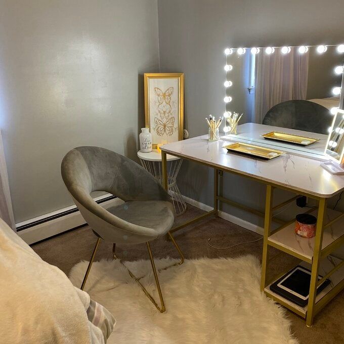 A reviewer's photo of a gray velvet papasan chair placed in front of their vanity.