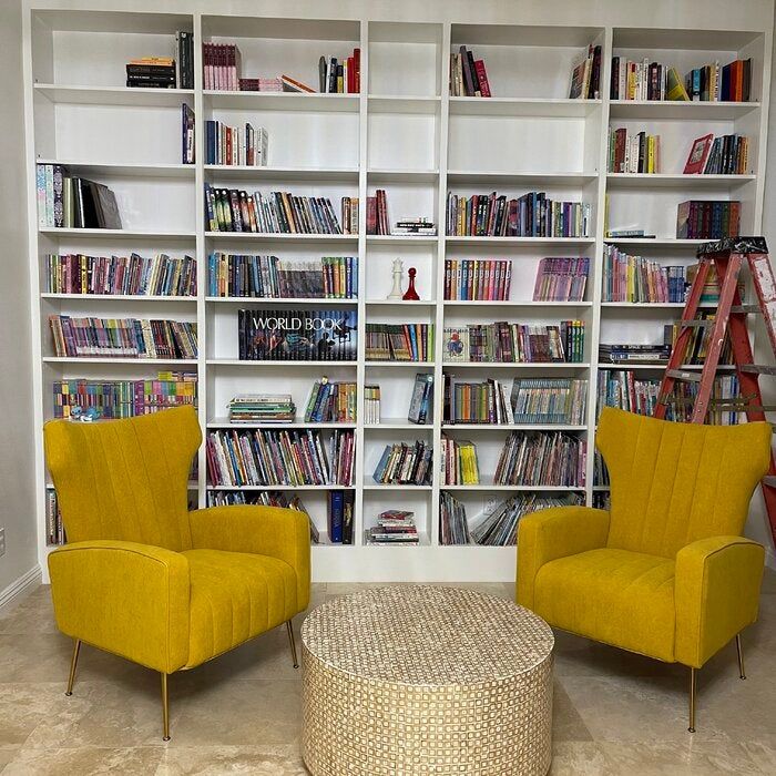 A photo from a reviewer showcasing two yellow velvet wingback chairs placed in their living room.