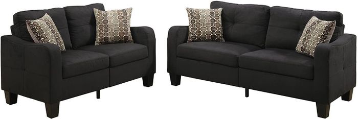 A pair of black couches with charming polka dot pillows set against a clean white backdrop