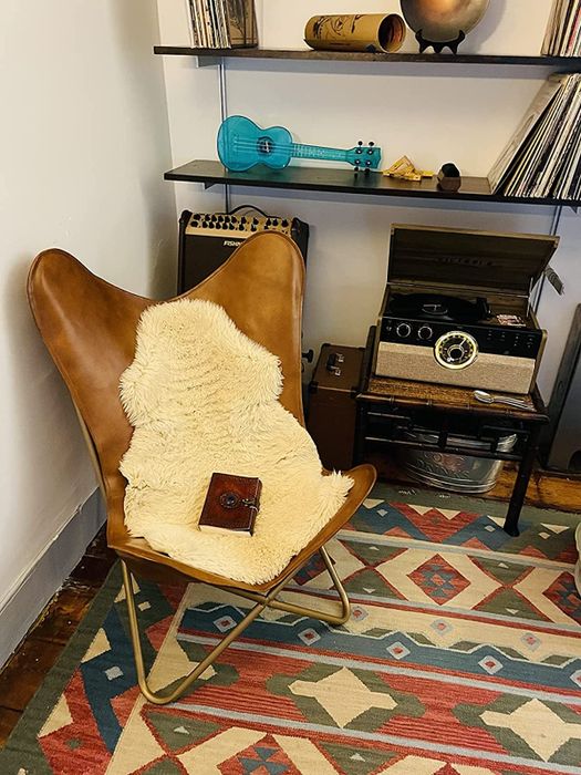 photo of the brown faux leather butterfly chair adorned with a cozy fur throw