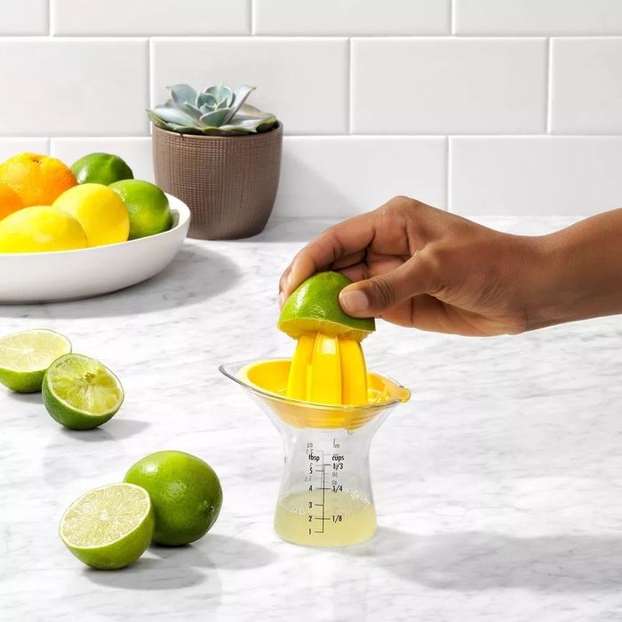 A person using the reamer to juice a lime
