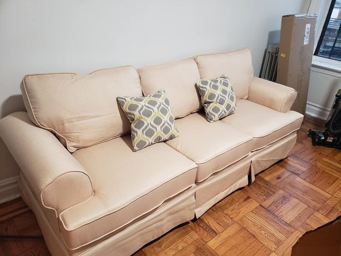 Reviewer photo showcasing a cream-colored couch with gray and yellow patterned throw pillows