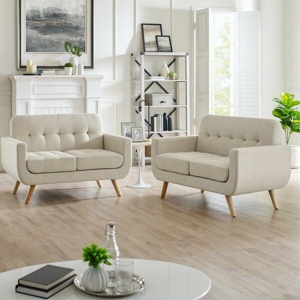 Two beige, rounded sofas on a wooden floor beside a round coffee table