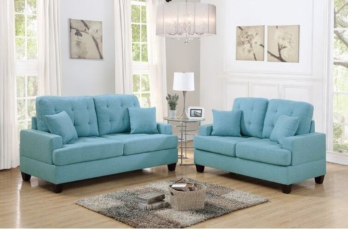 Two striking blue couches set around a rug with brown and gray squares and a basket overflowing with books