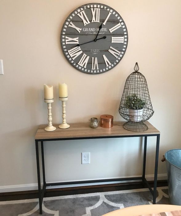 A reviewer's photo showing a narrow console table with a wooden top and metal legs, positioned against a wall.
